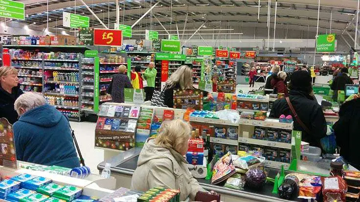 A photo of ASDA checkout staff working hard while customers queue at the checkouts