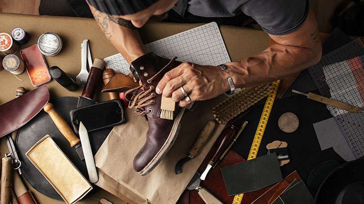 Photo of a shoe maker using various materials to make a pair of shoes for a retail worker